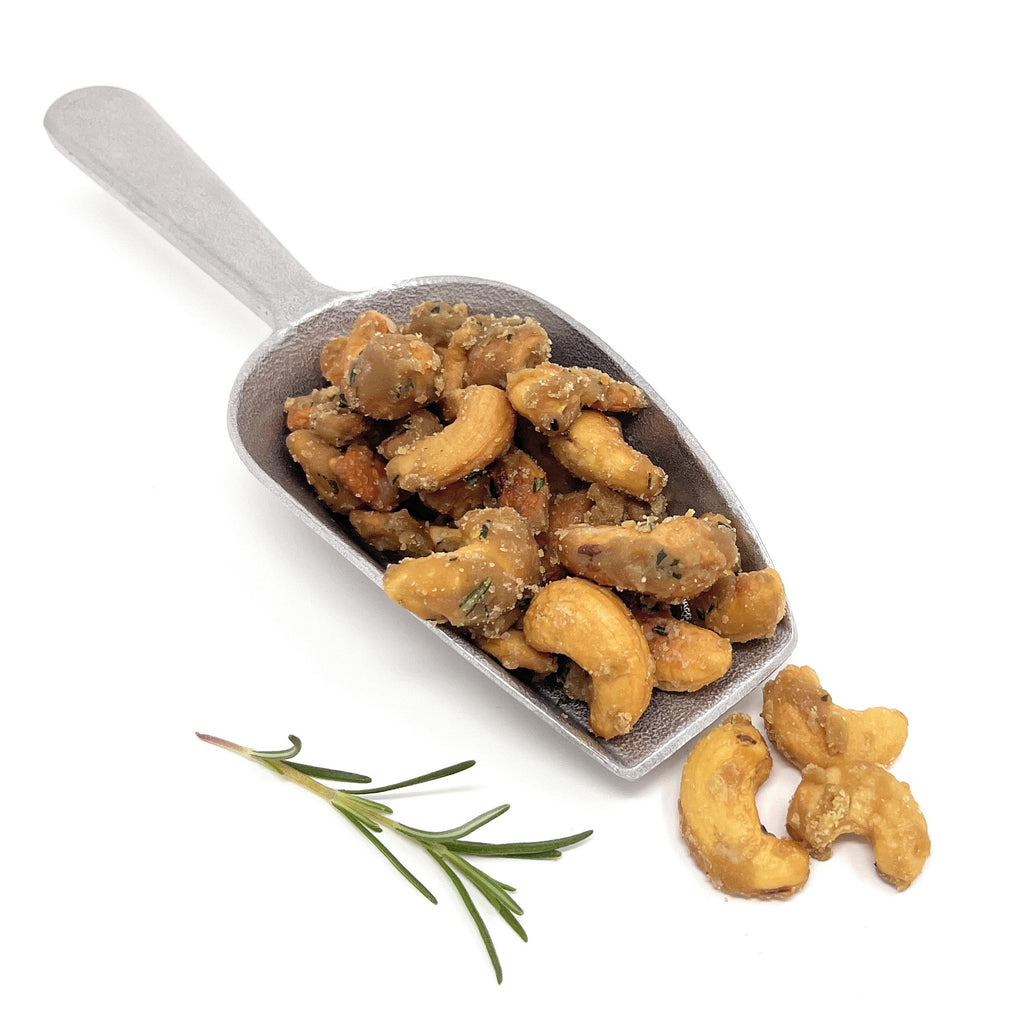 Metal scoop filled with cashews on a white background