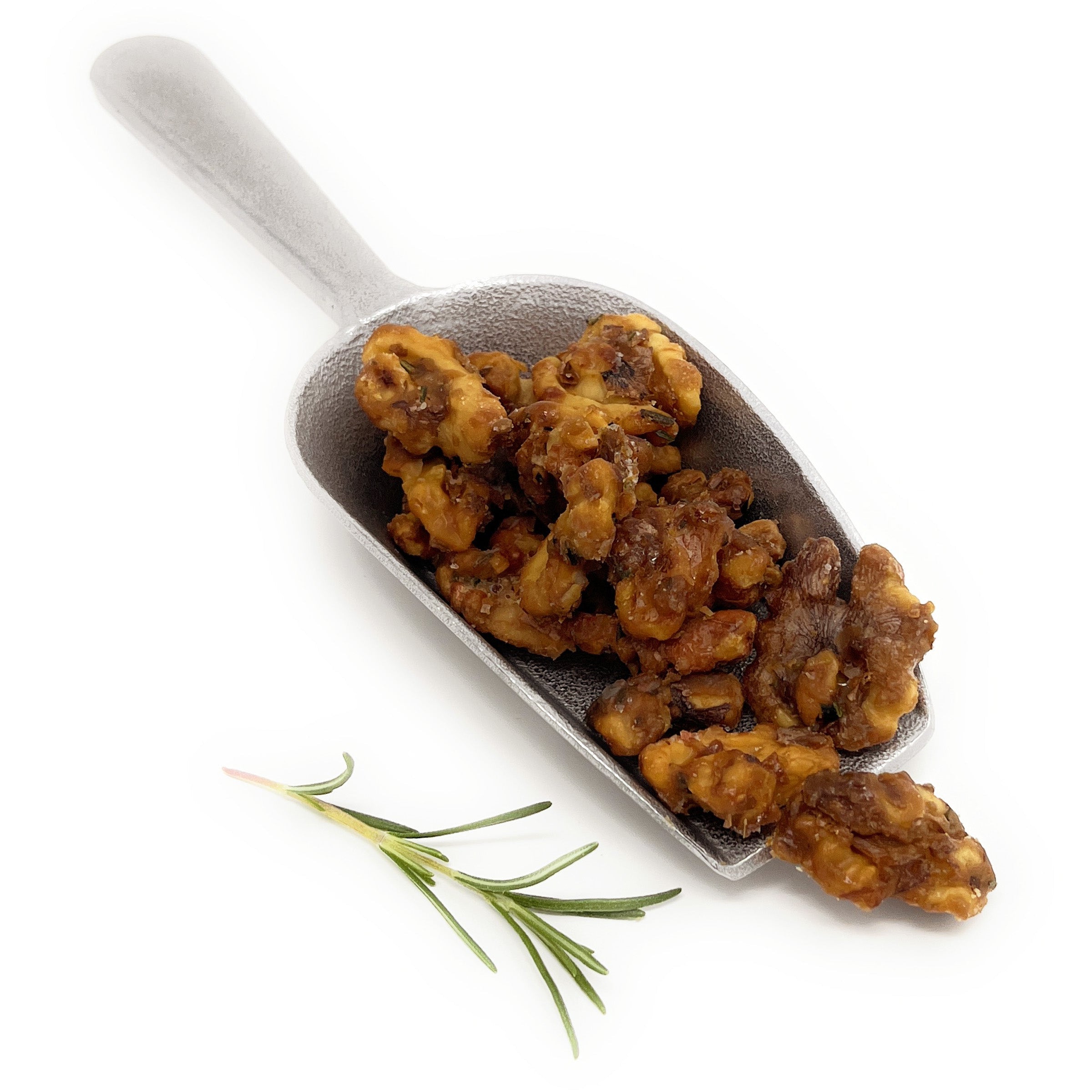 Metal scoop filled with roasted walnuts on a white background